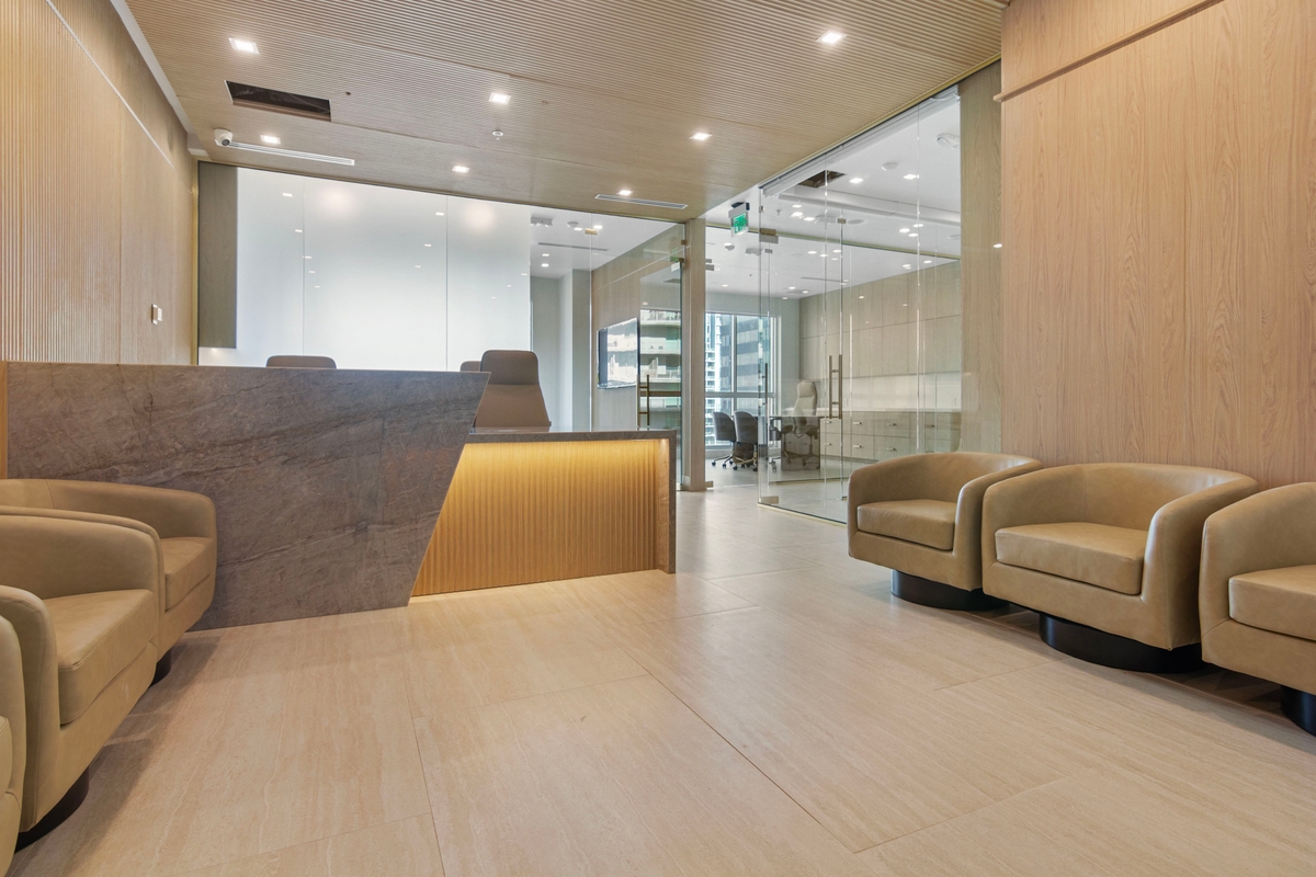 Reception lounge with stone-clad desk surround and glass-enclosed offices at Latitude One Suites 1707–1710